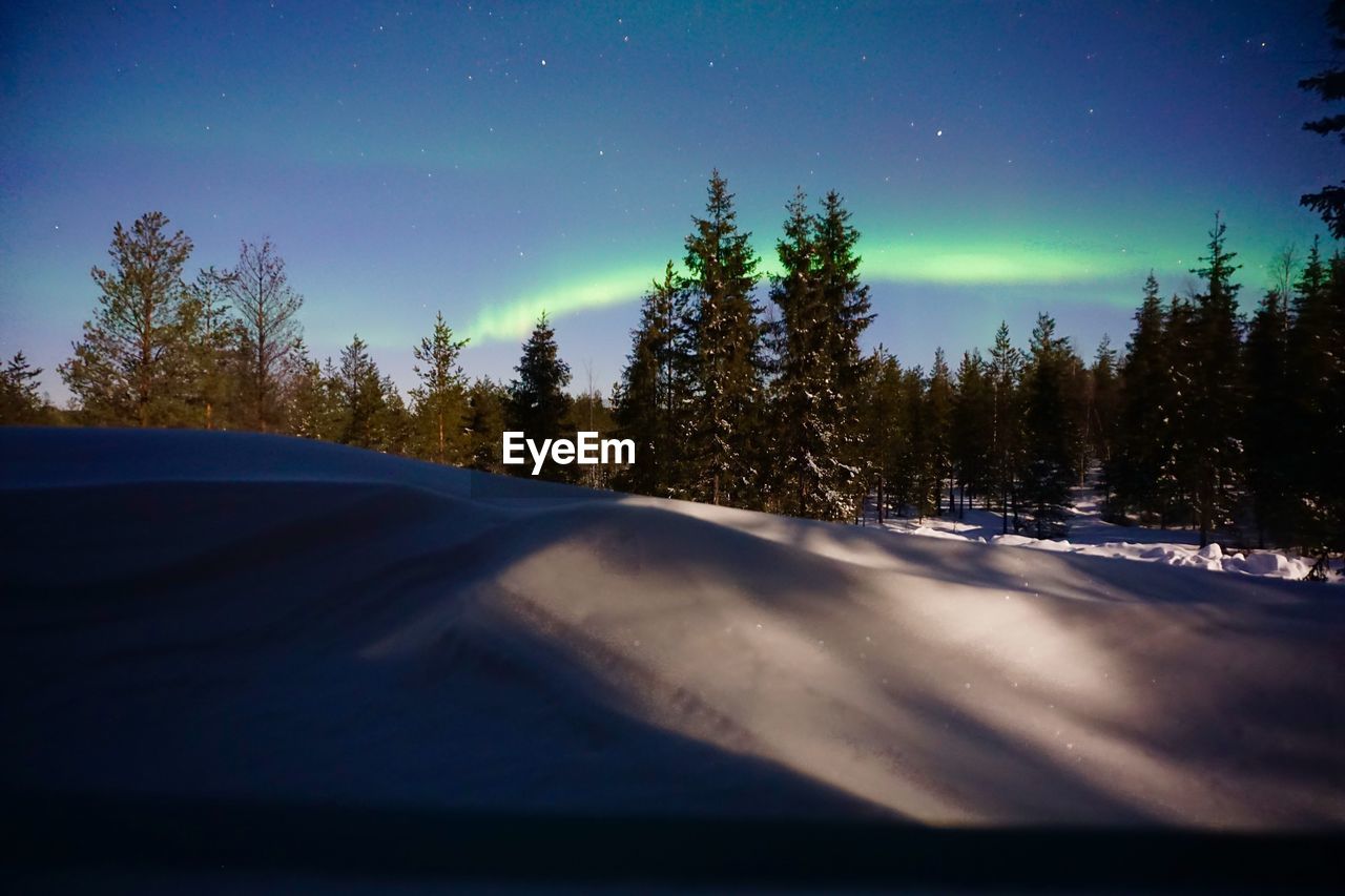 Snow covered landscape against sky at night