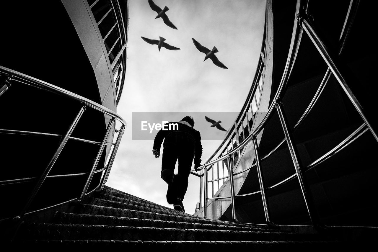 LOW ANGLE VIEW OF MAN FLYING BY BUILDING