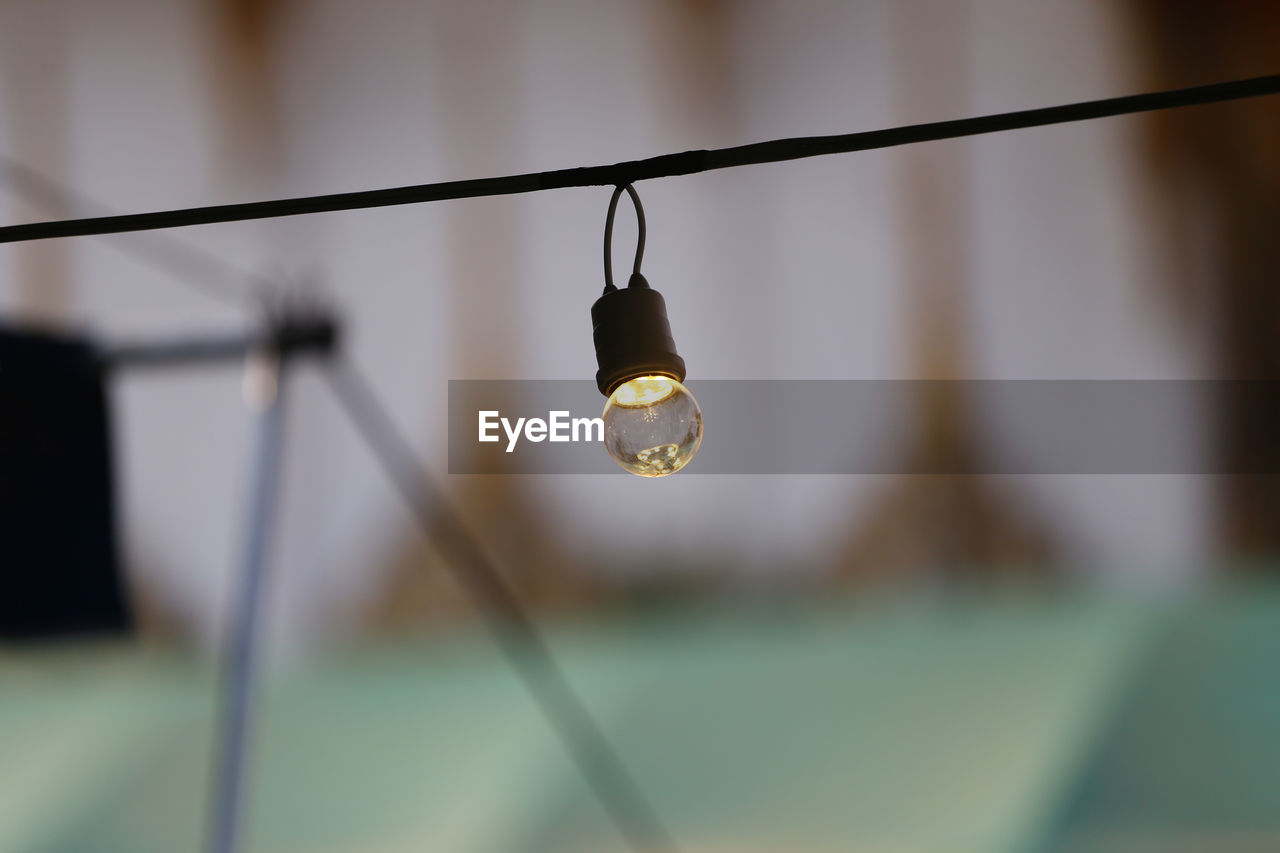 hanging, focus on foreground, lighting equipment, illuminated, no people, lighting, light, light bulb, electricity, close-up, cable, indoors, selective focus, light fixture