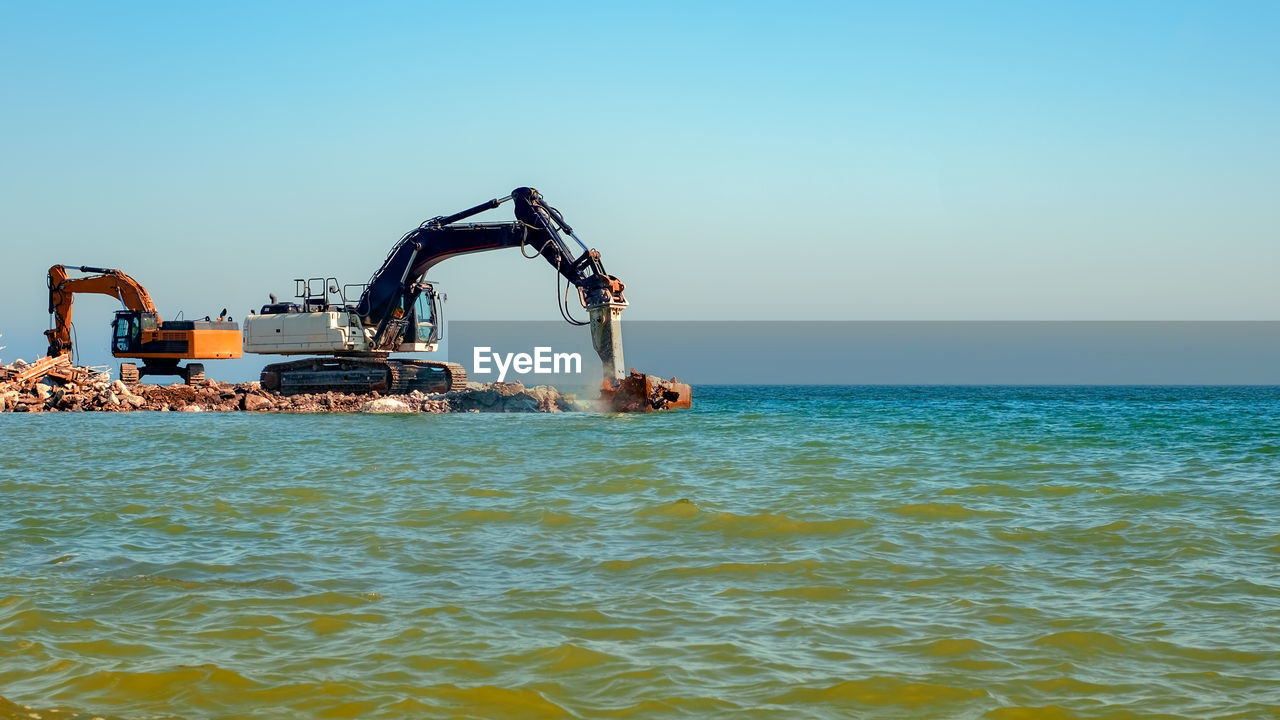 Excavators crashing concrete into the sea