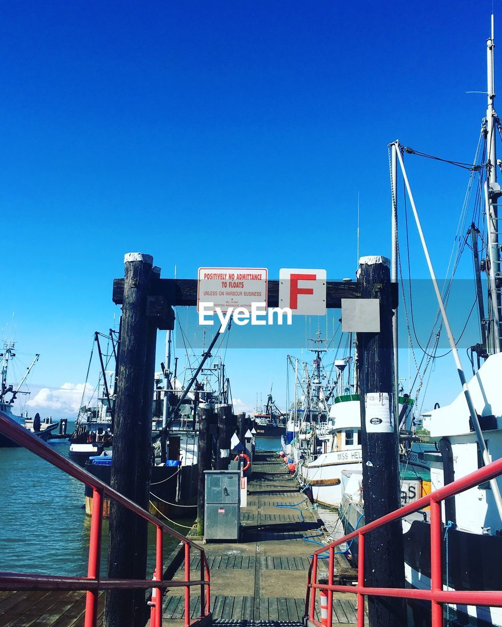 Boats moored at harbor against clear blue sky