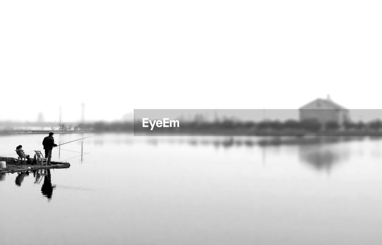 Couple fly-fishing on jetty in river