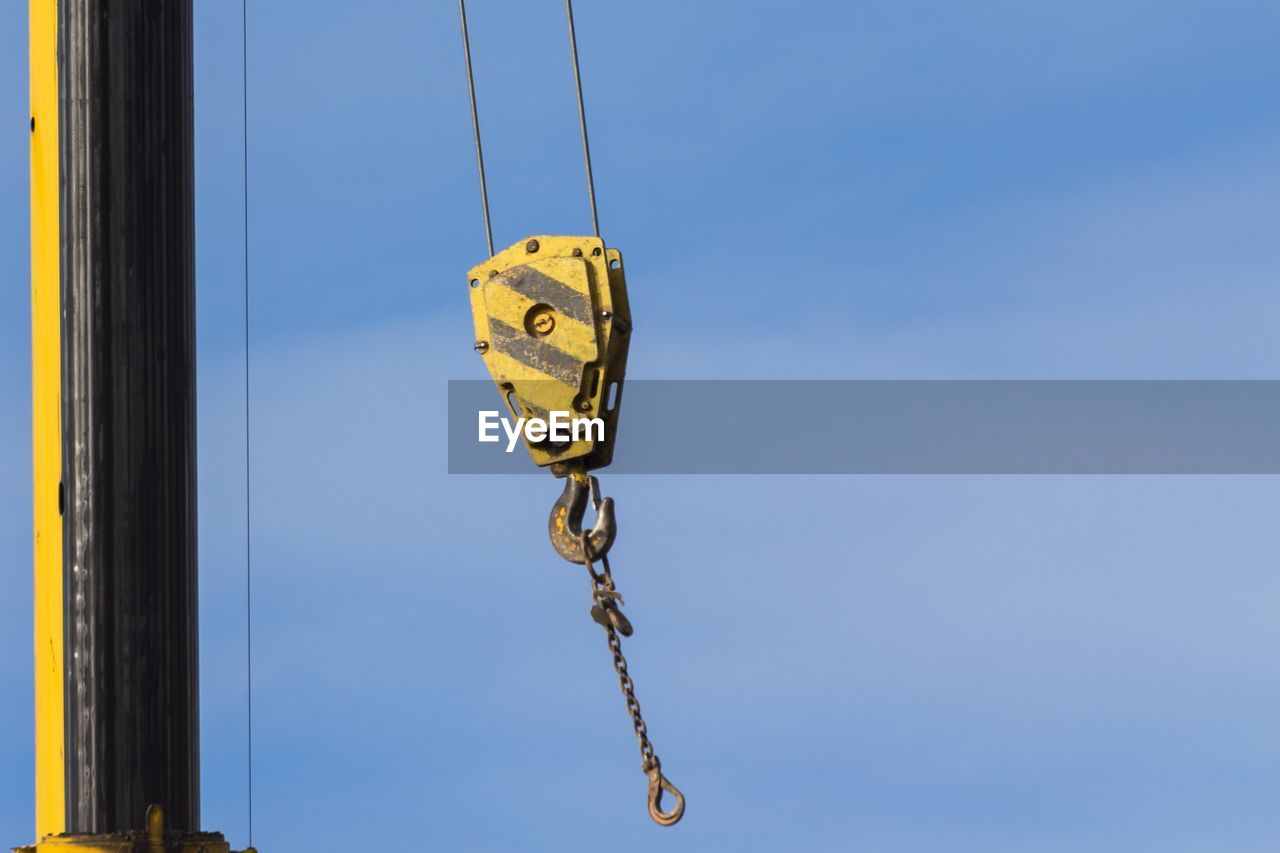 Low angle view of hook hanging against sky