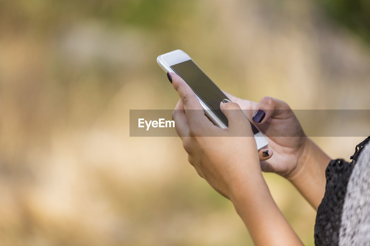 Cropped hands of woman using mobile phone