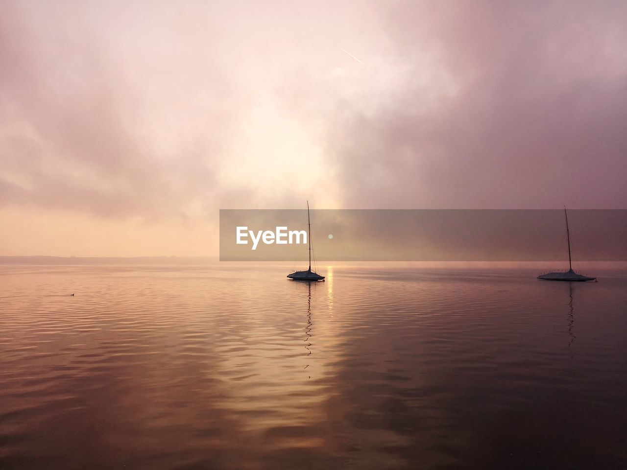 Sailboat in sea against sky during sunset