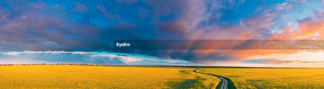 SCENIC VIEW OF FIELD AGAINST CLOUDY SKY DURING SUNSET