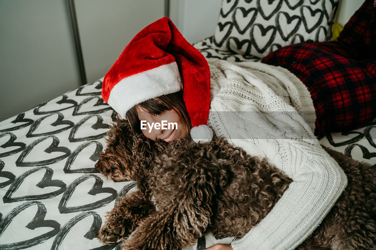 Smiling woman relaxing with dog on bed at home