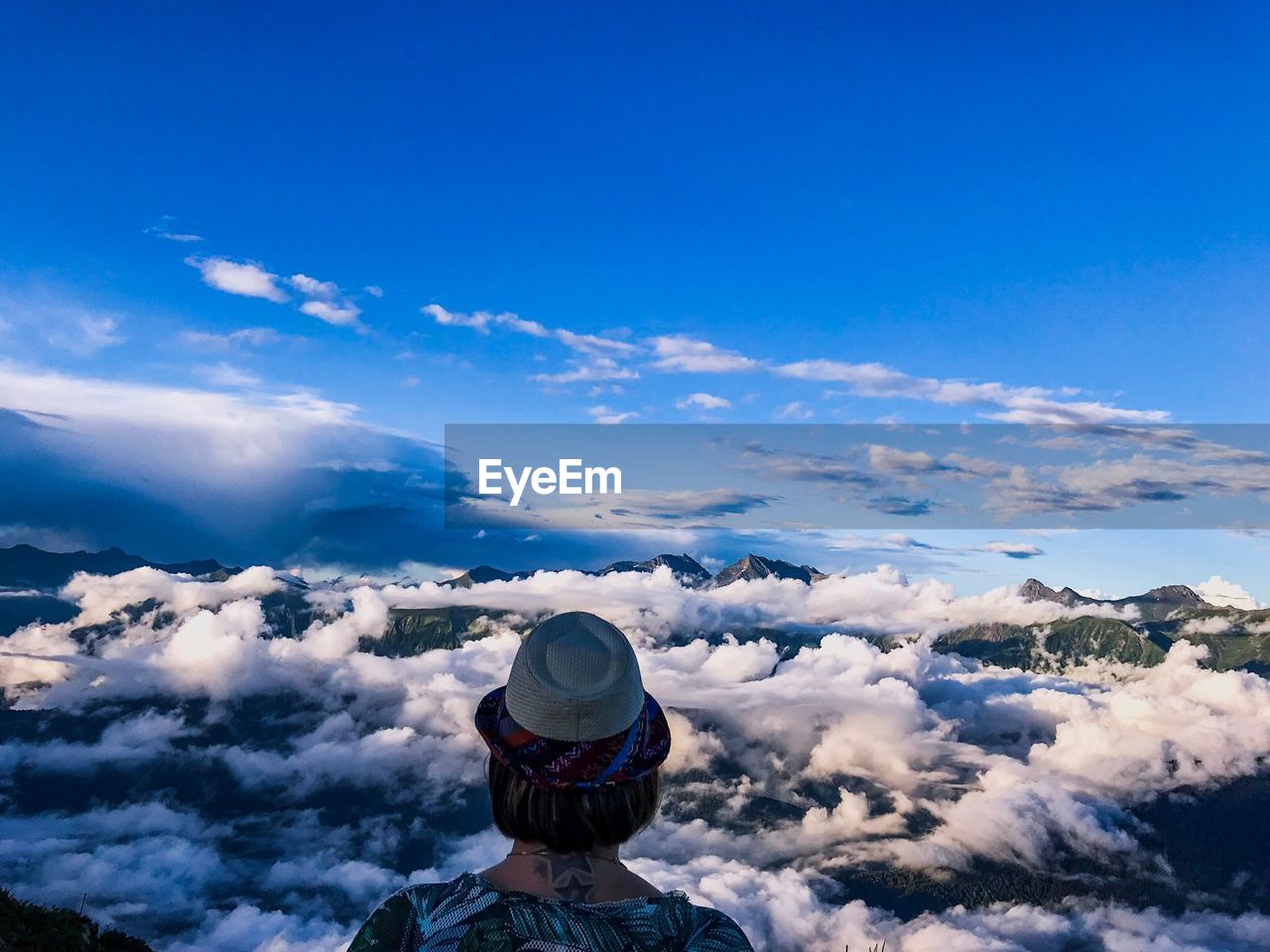 REAR VIEW OF WOMAN ON MOUNTAIN AGAINST SKY