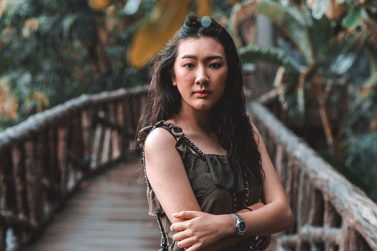 PORTRAIT OF WOMAN STANDING ON FOOTBRIDGE