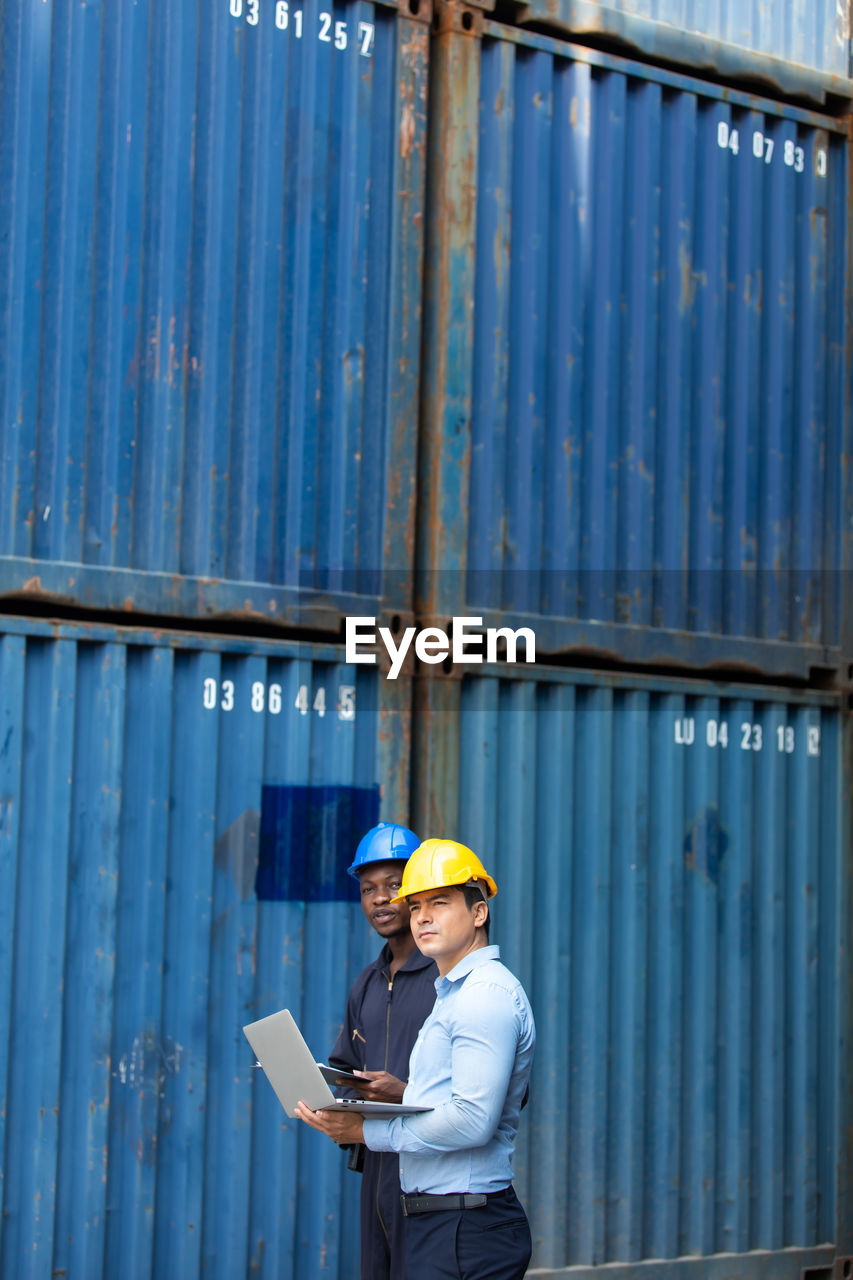 MAN WORKING WITH SMART PHONE STANDING ON LAPTOP