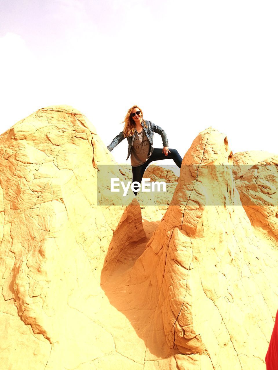 Portrait of woman standing on rock against sky