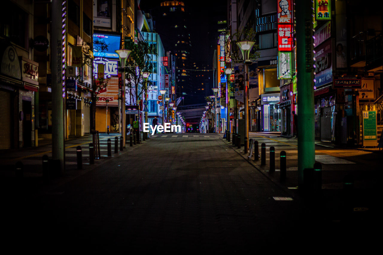 Illuminated street amidst buildings in ikebukuro city at night