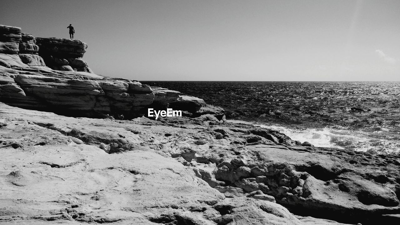 Rocky sea shore against clear sky