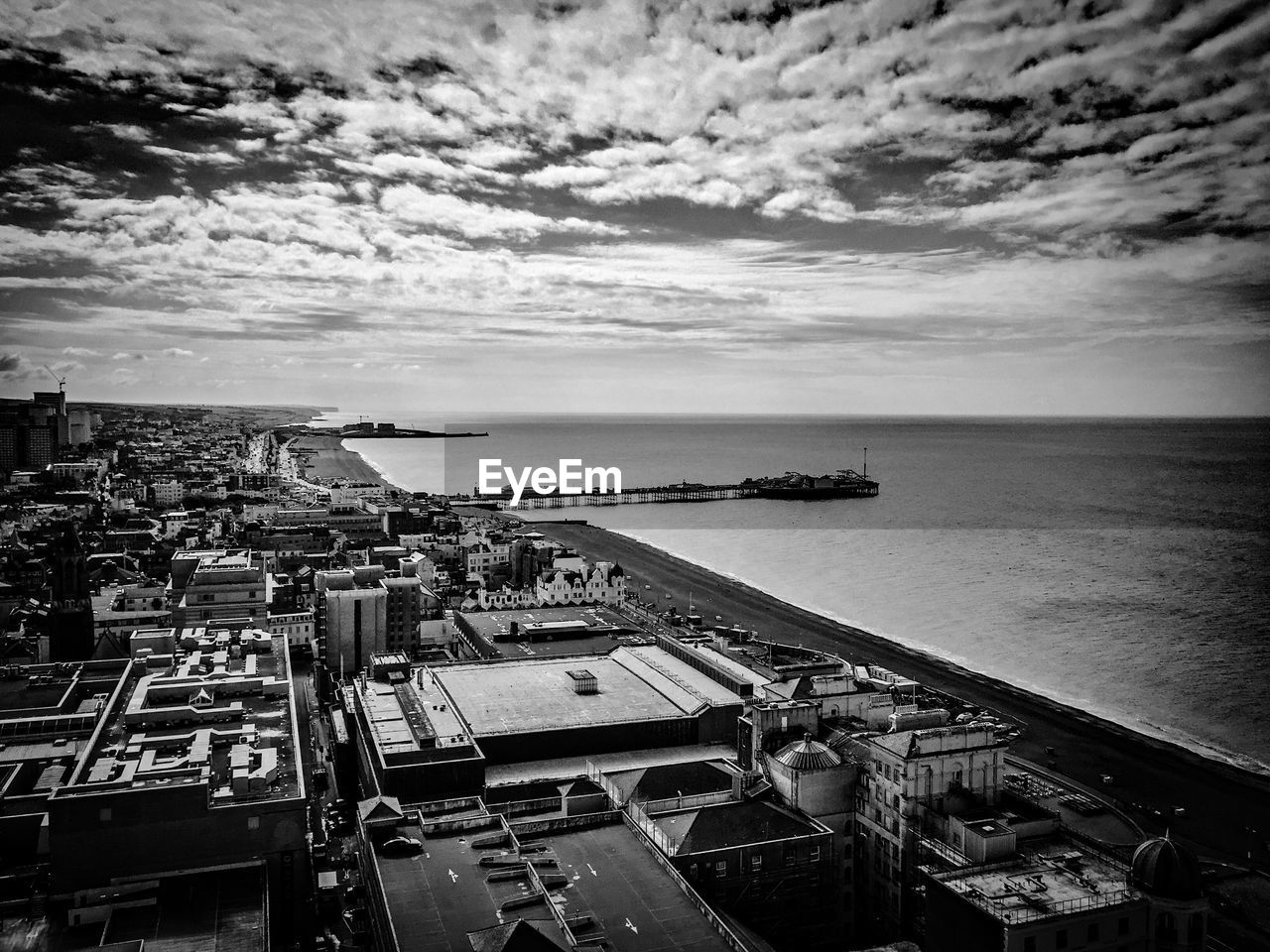 Brighton pier on sea against cloudy sky in city