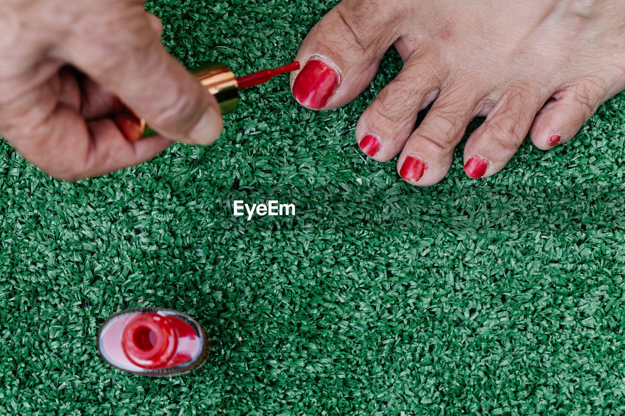 Old man painting his wife's toenails red seen from above