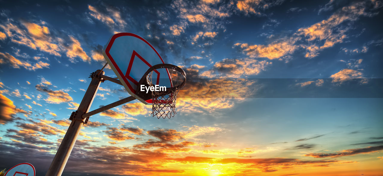 LOW ANGLE VIEW OF BASKETBALL HOOP AGAINST SUNSET SKY