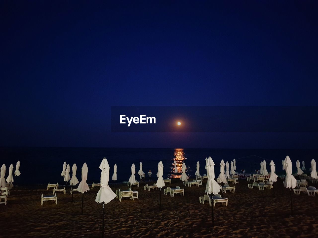 Chairs on beach against clear sky at night