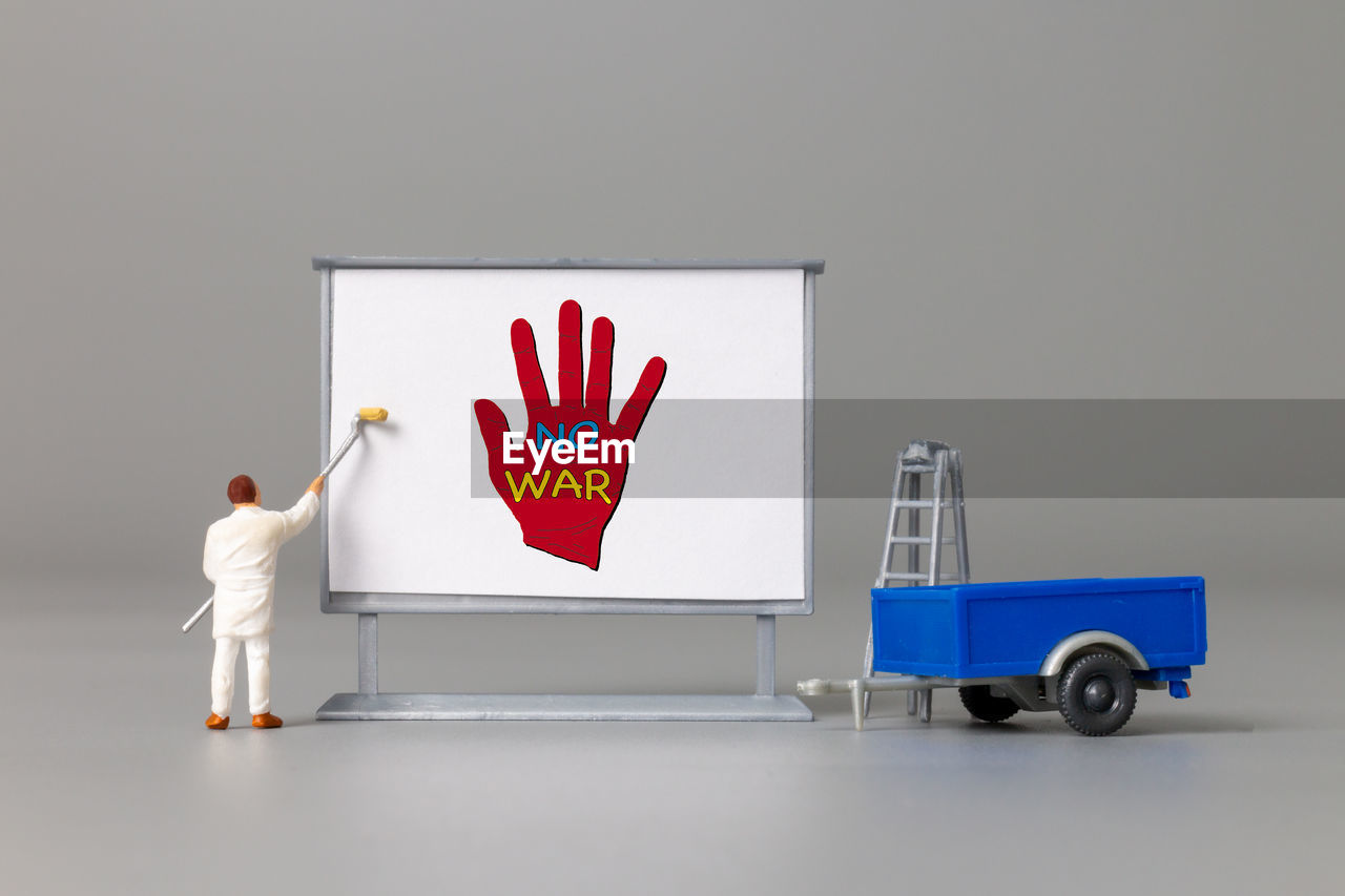 Miniature people painter at the front of a whiteboard painted no war