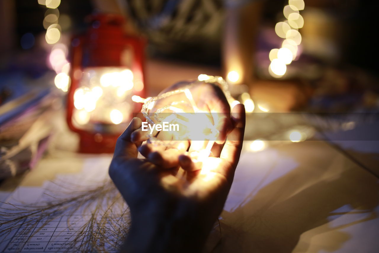 Close-up of hands holding illuminated lighting equipment