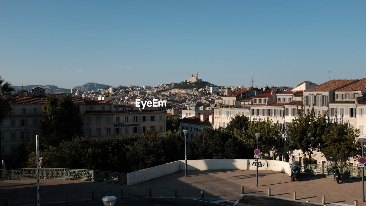 Buildings in city against clear blue sky