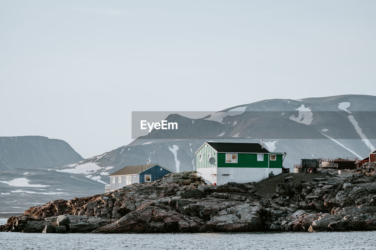 Sea by houses on snow covered mountain