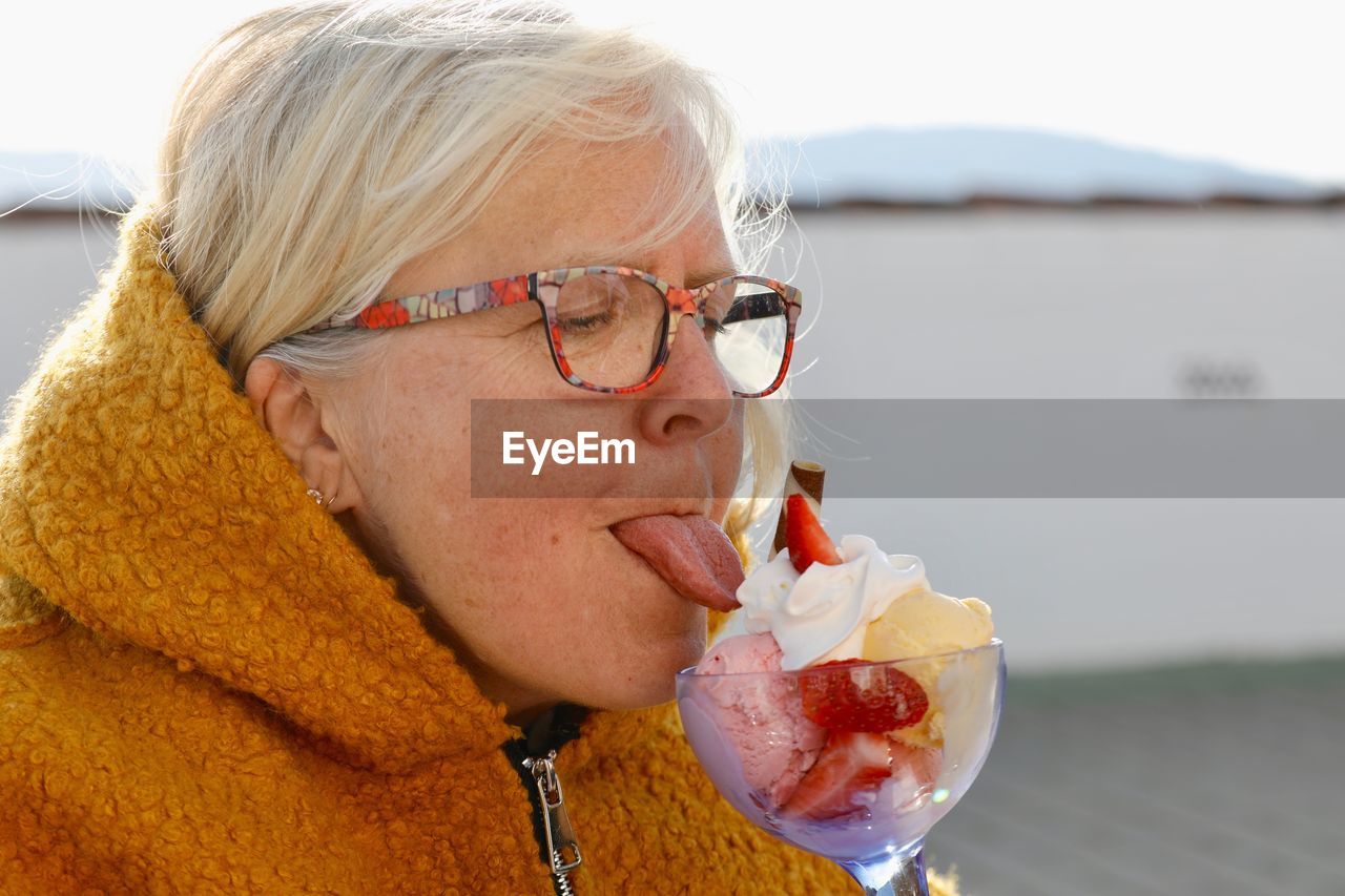 Close-up of senior woman licking ice cream in glass