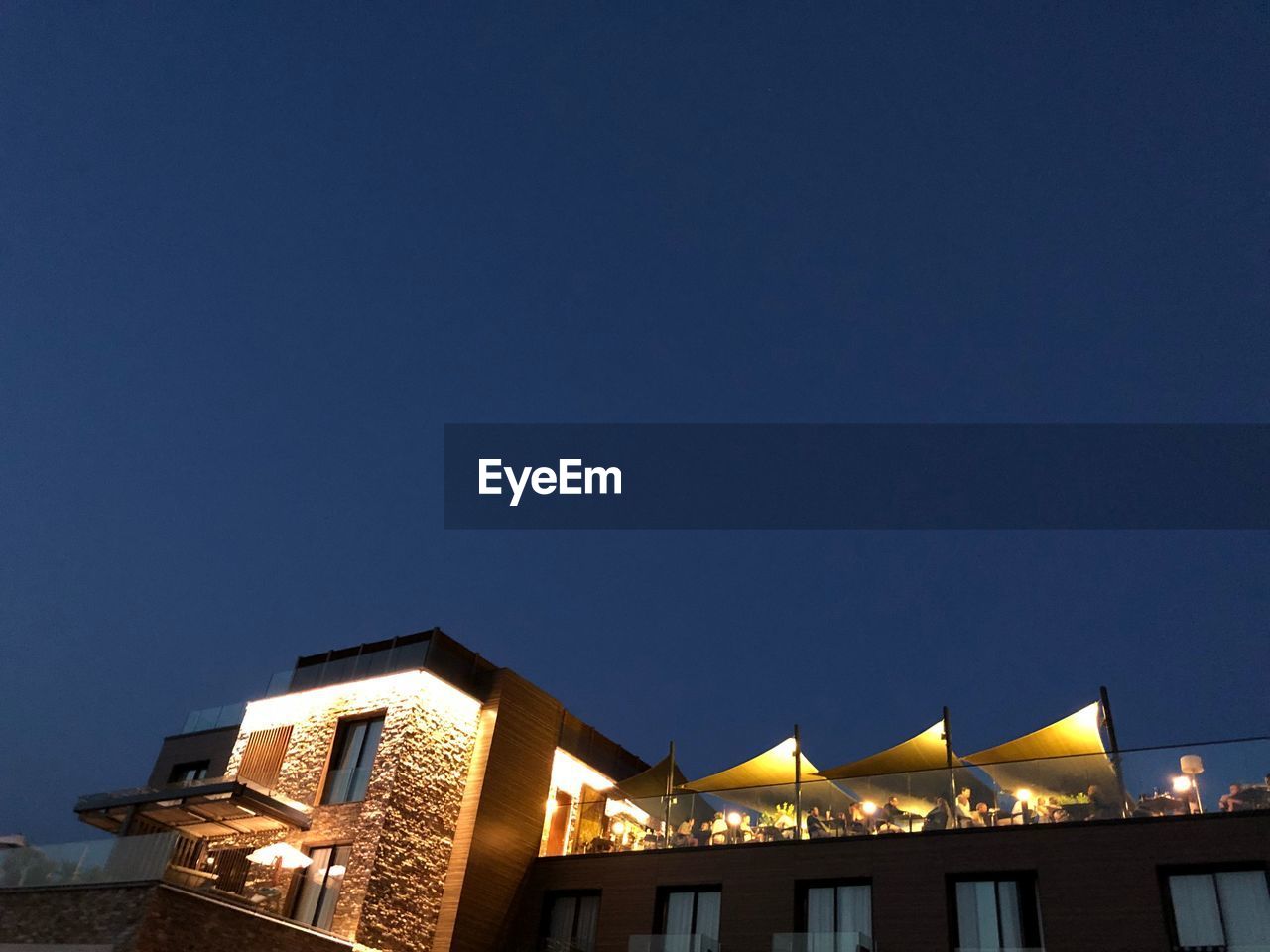 LOW ANGLE VIEW OF ILLUMINATED BUILDINGS AGAINST CLEAR SKY