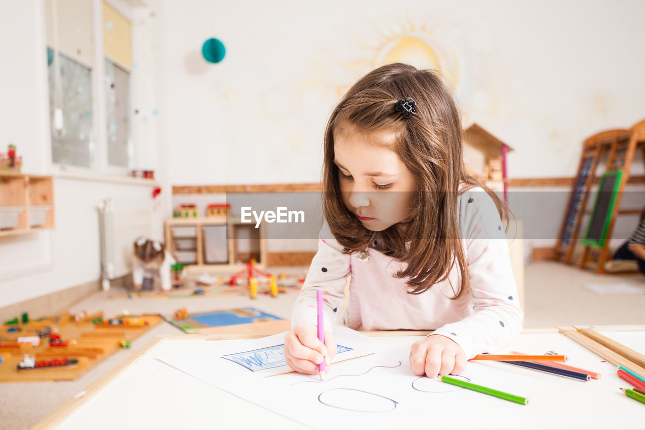 Girl looking away while sitting on table at home