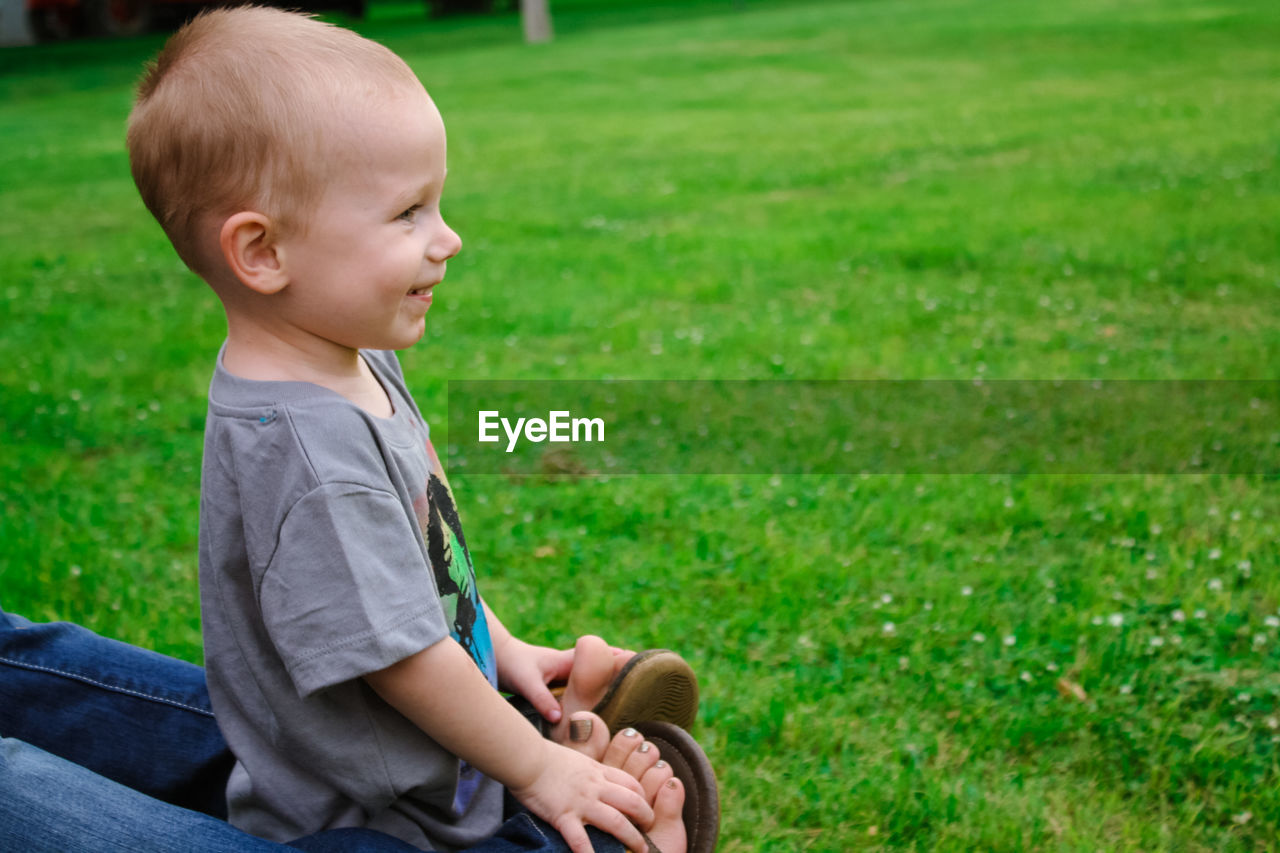 Low section of mother legs wrapped amidst son standing on grassy field