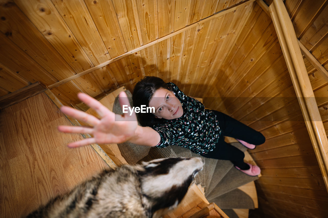 Portrait of young woman gesturing with hand on wooden spiral staircase 