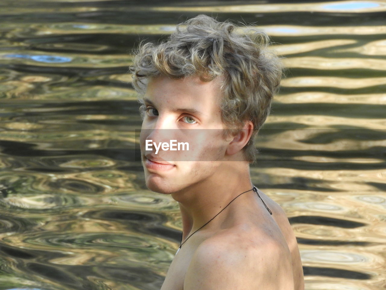 Portrait of shirtless young man in sea