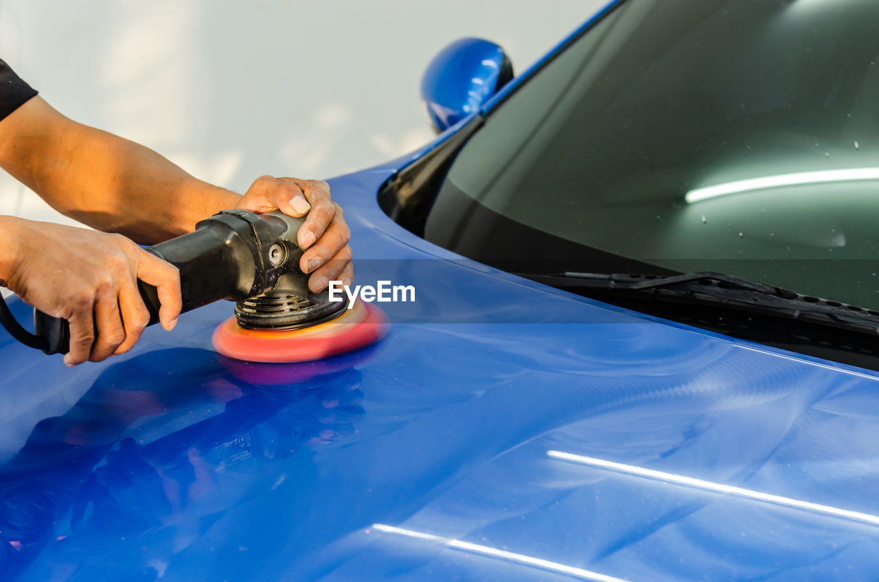 Cropped hands of man washing car