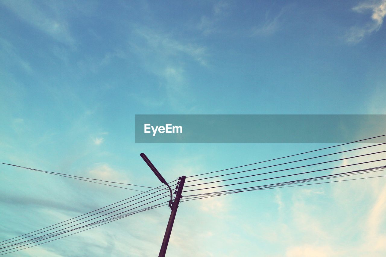 Low angle view of power lines against blue sky