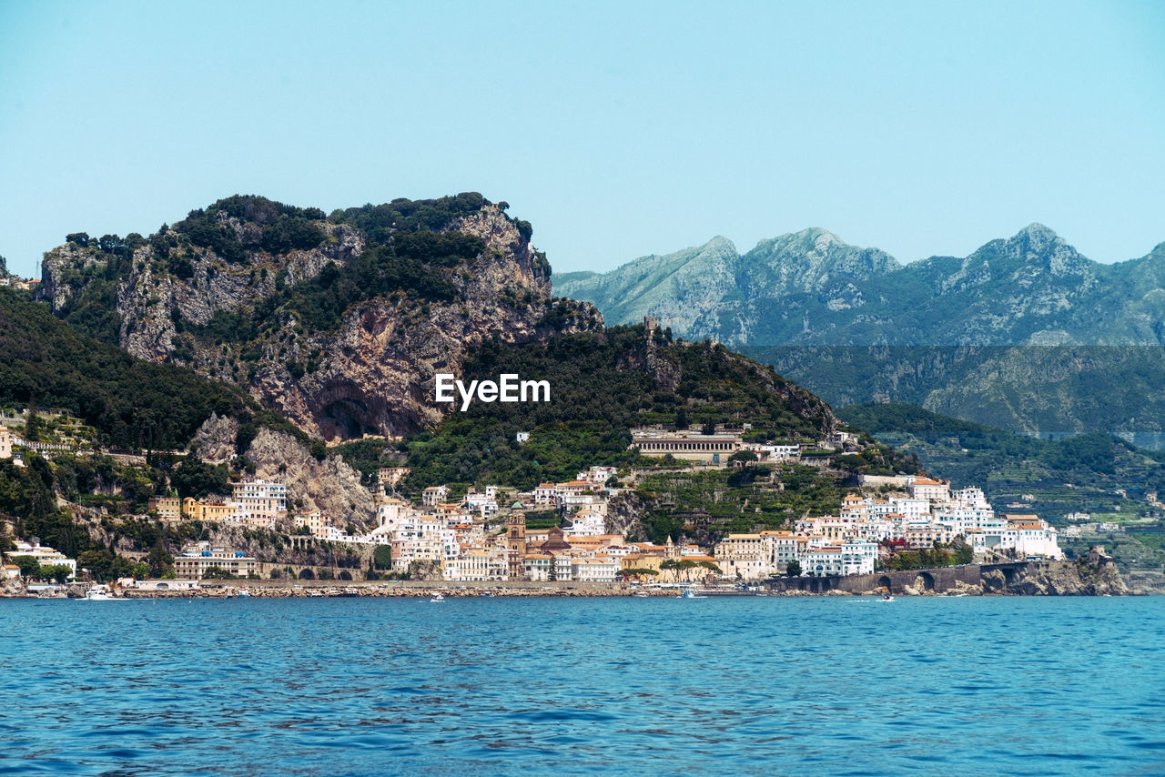 SCENIC VIEW OF SEA BY TOWNSCAPE AGAINST CLEAR BLUE SKY