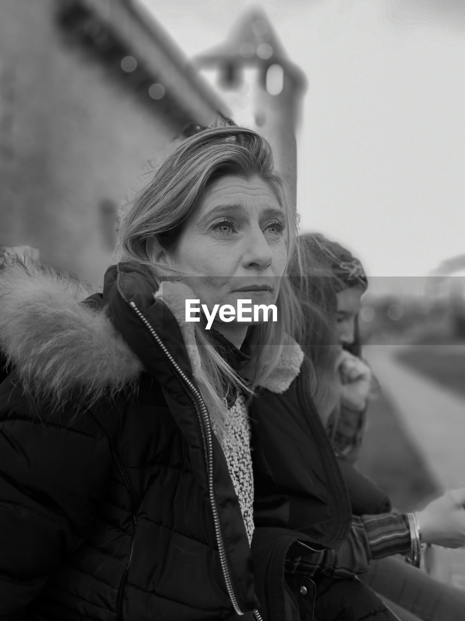 Thoughtful woman wearing warm clothing sitting outdoors