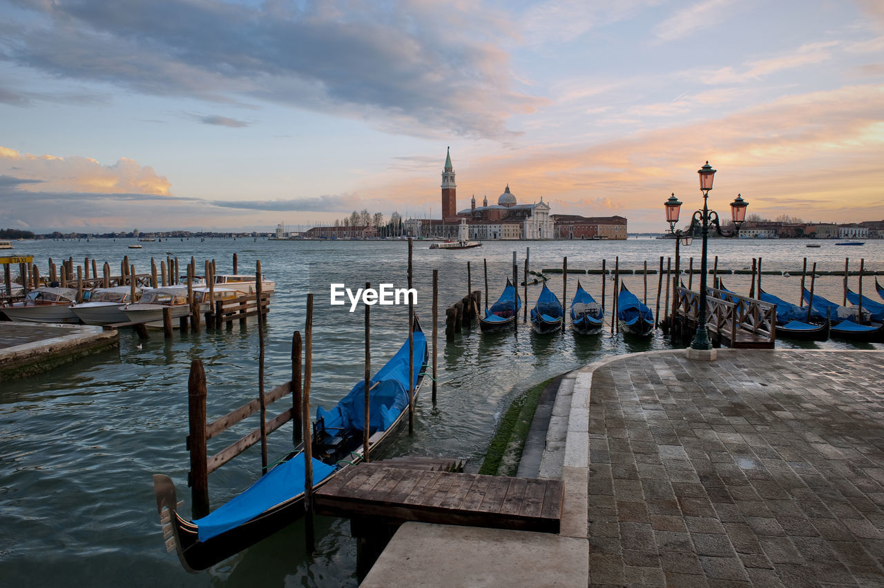 Gondolas moored at grand canal by santa maria della salute against sky