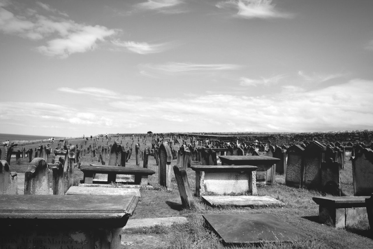 Tombstones in graveyard against cloudy sky