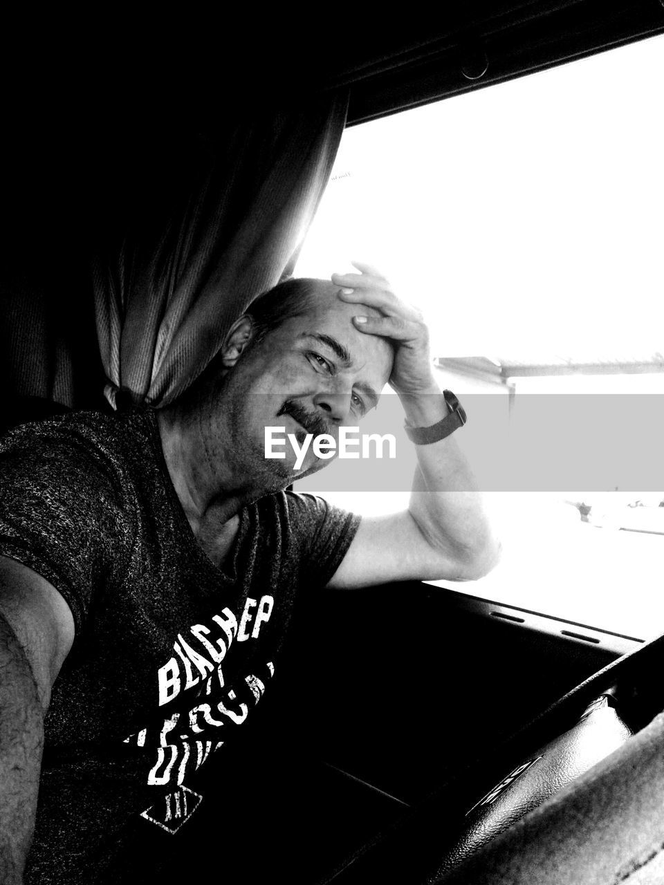 Portrait of mature man sitting by window in vehicle