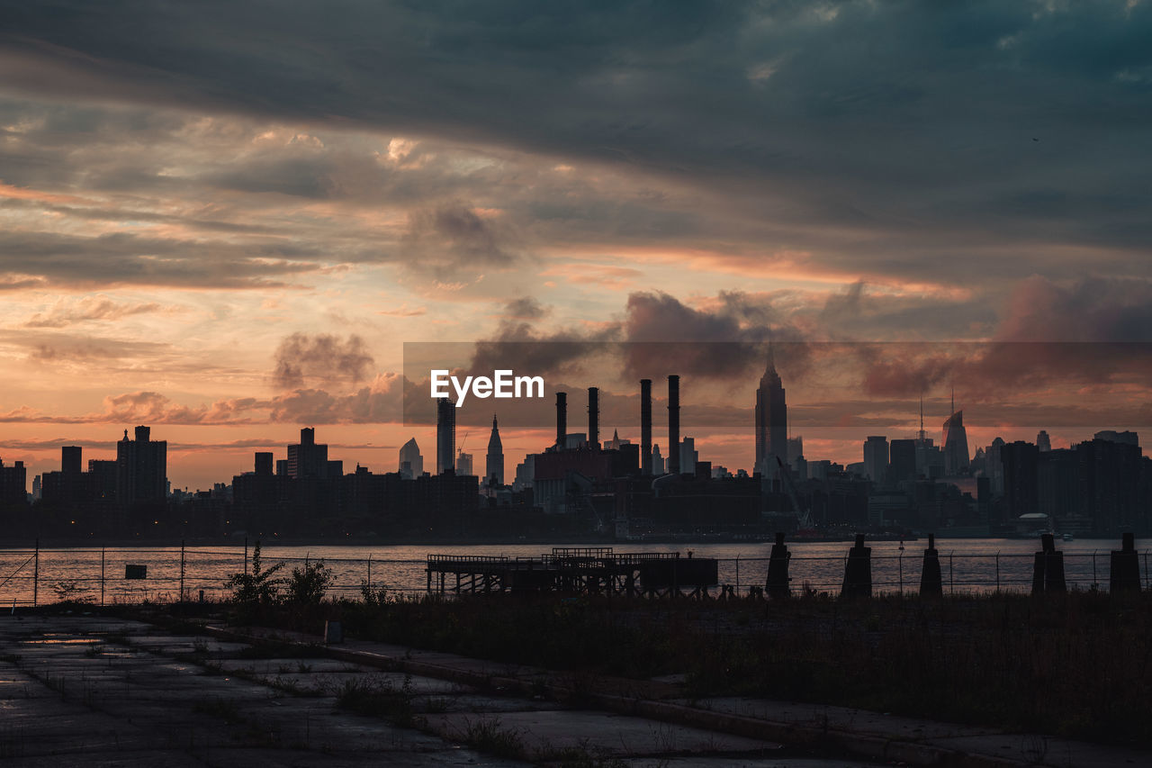 Cityscape and river against sky during sunset