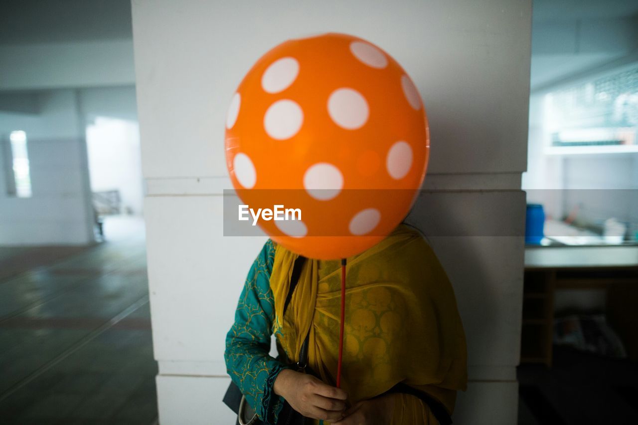 Close-up of woman holding balloon in front of her face