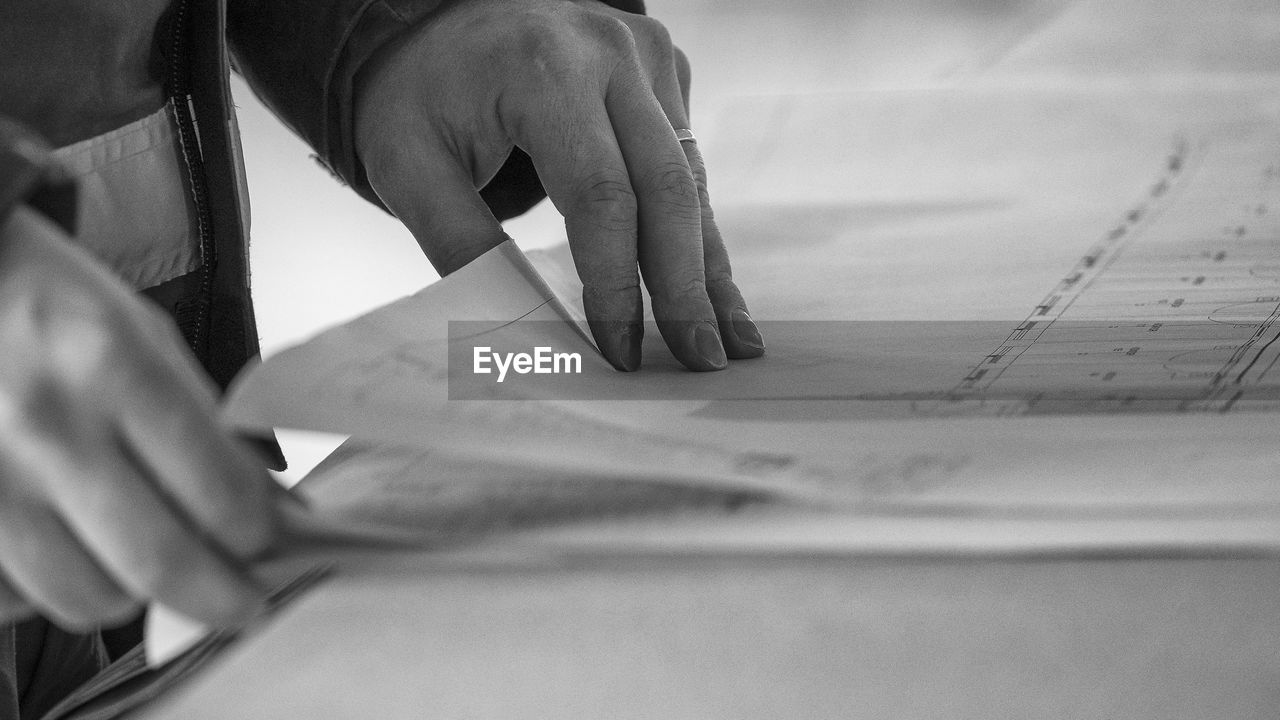 Midsection of male architect with blueprint at desk