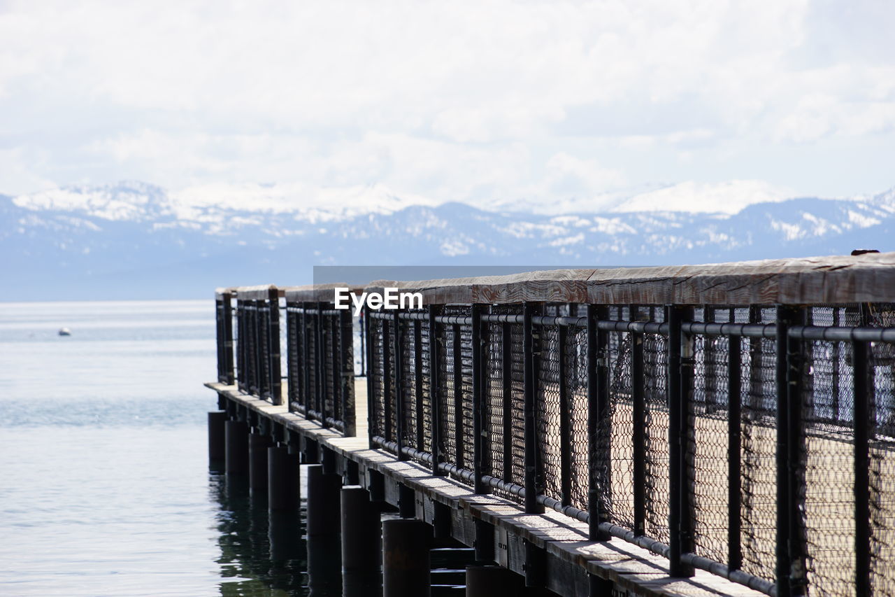 Wooden posts on pier over sea against sky