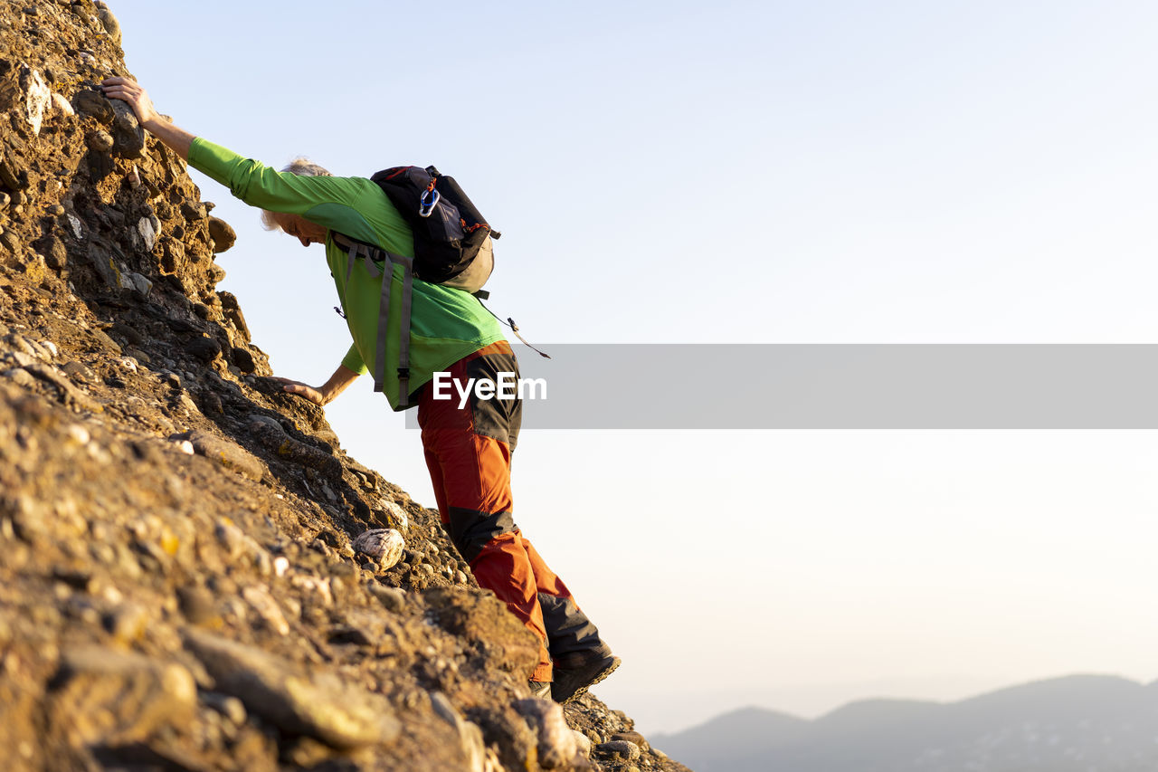 Senior man hiking a mountain during sunny day