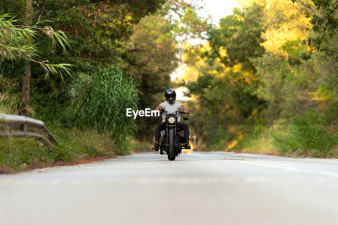 Young man on a vintage motorcycle on a mountain road at sunset