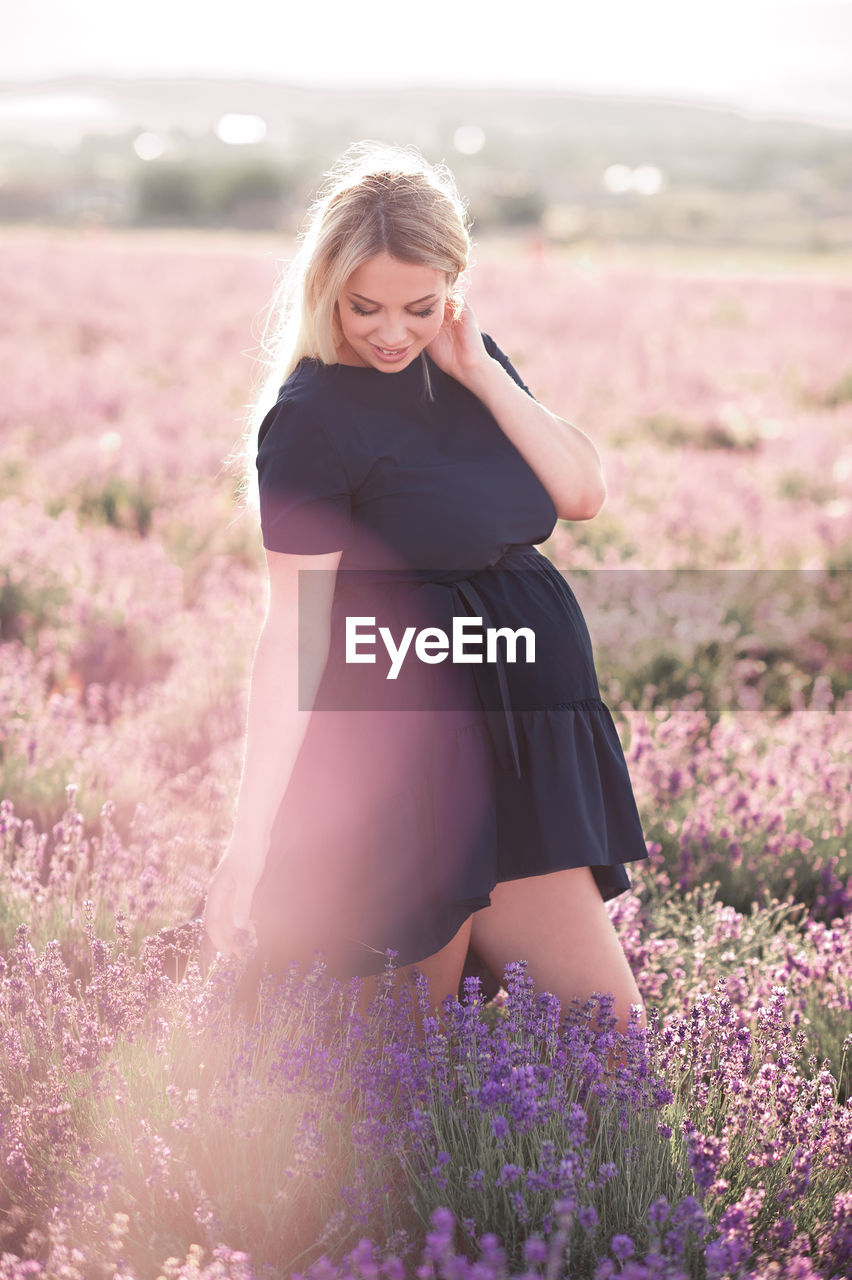 Happy pregnant woman standing on field