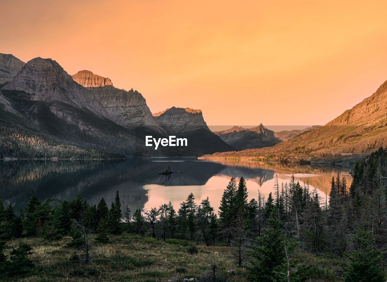 Scenic view of lake and mountains against sky during sunset