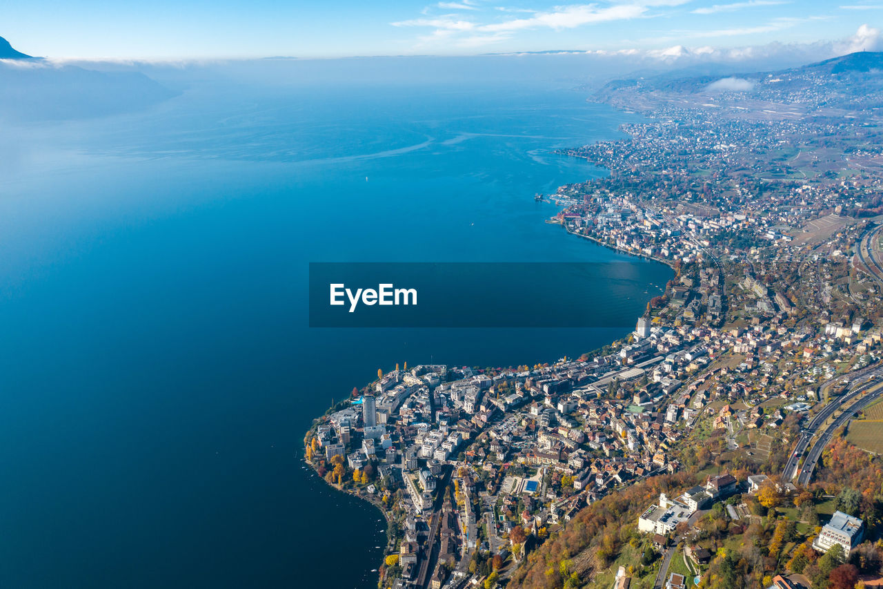 Aerial view of city by sea against sky