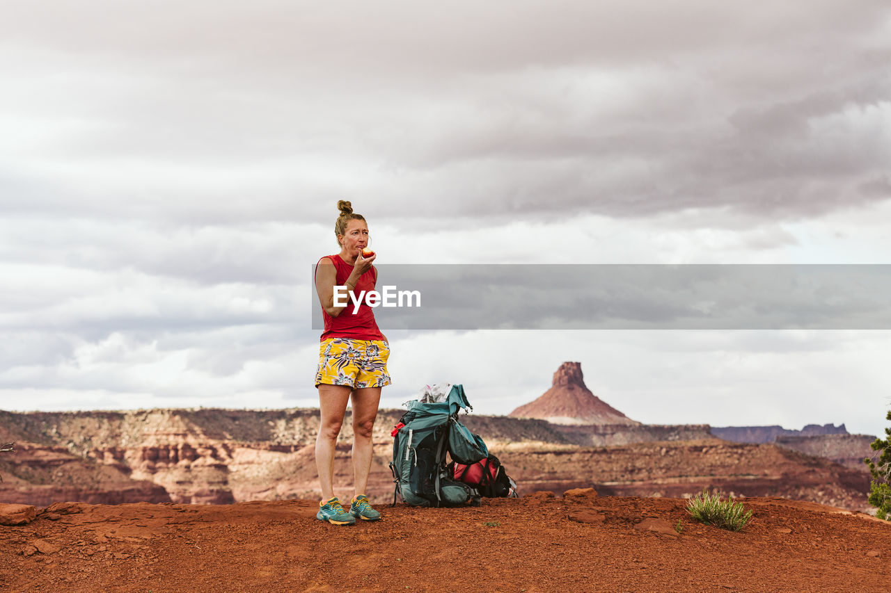 Tired female hiker eats apple during a long day backpacking in desert