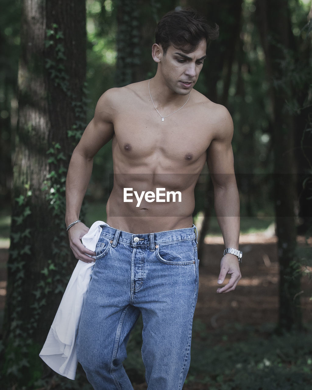 Shirtless man standing in forest