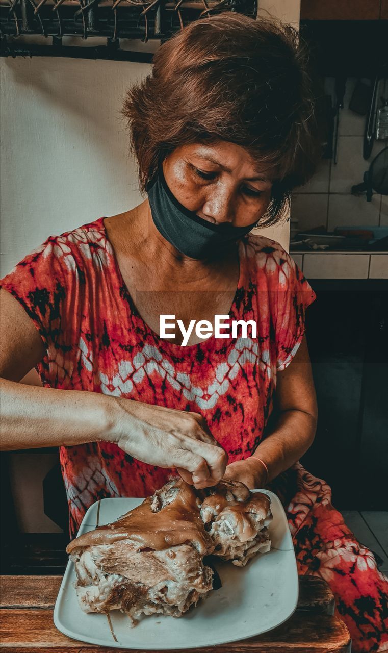 Woman wearing mask cooking food in kitchen